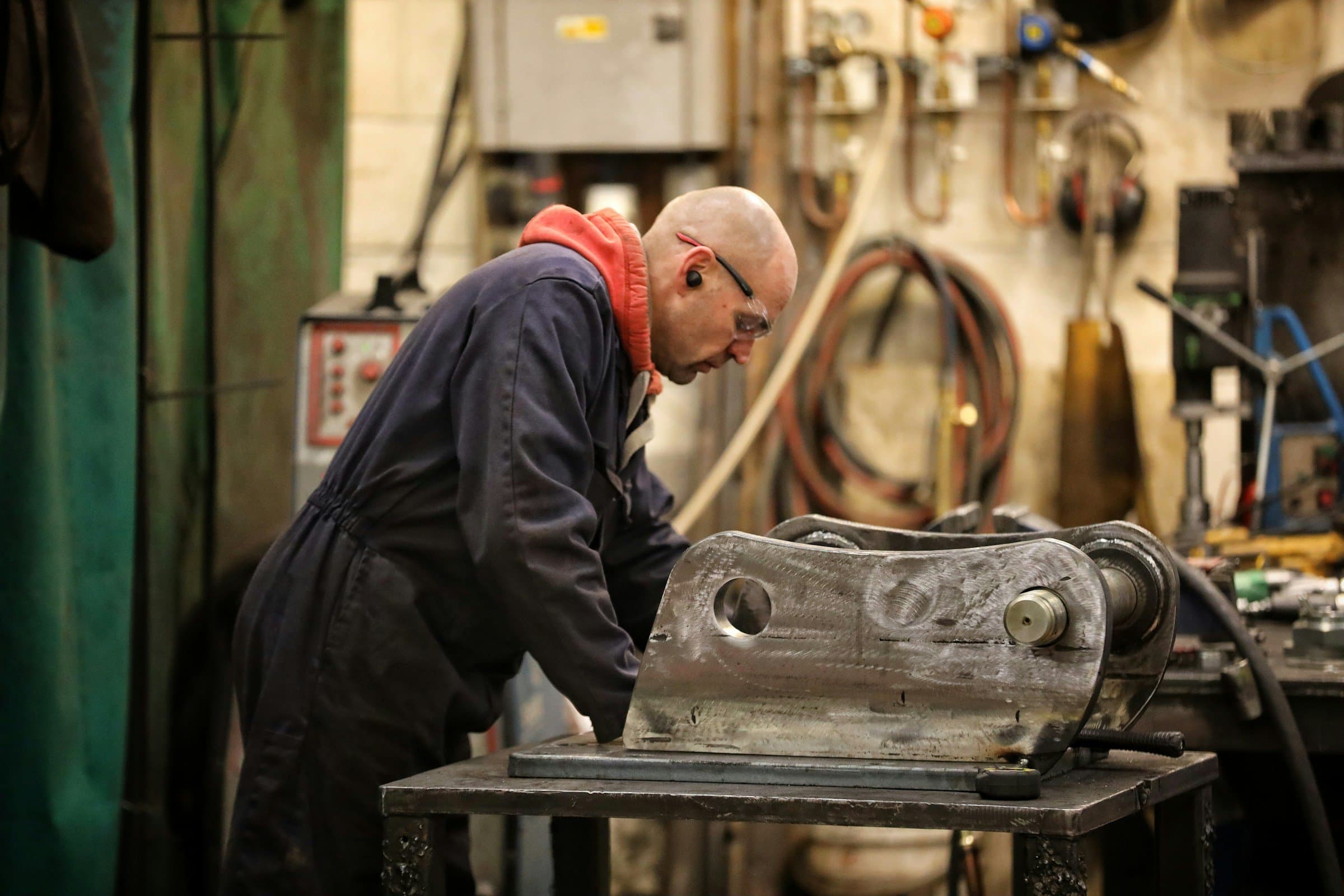 A fabricator works on a heavy steel part in a machine shop.