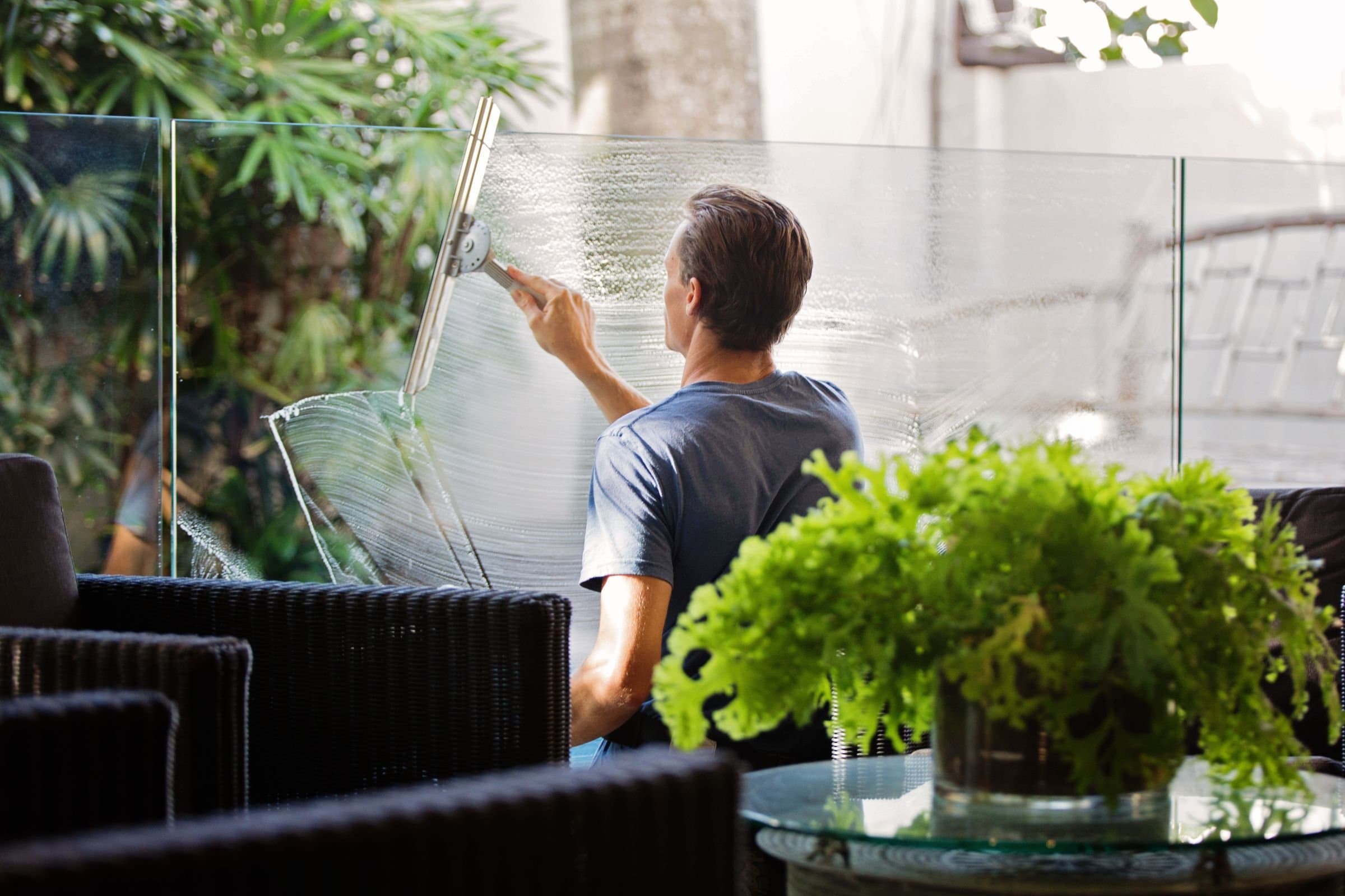 A window cleaner squeegees a glass balustrade in a lounge.